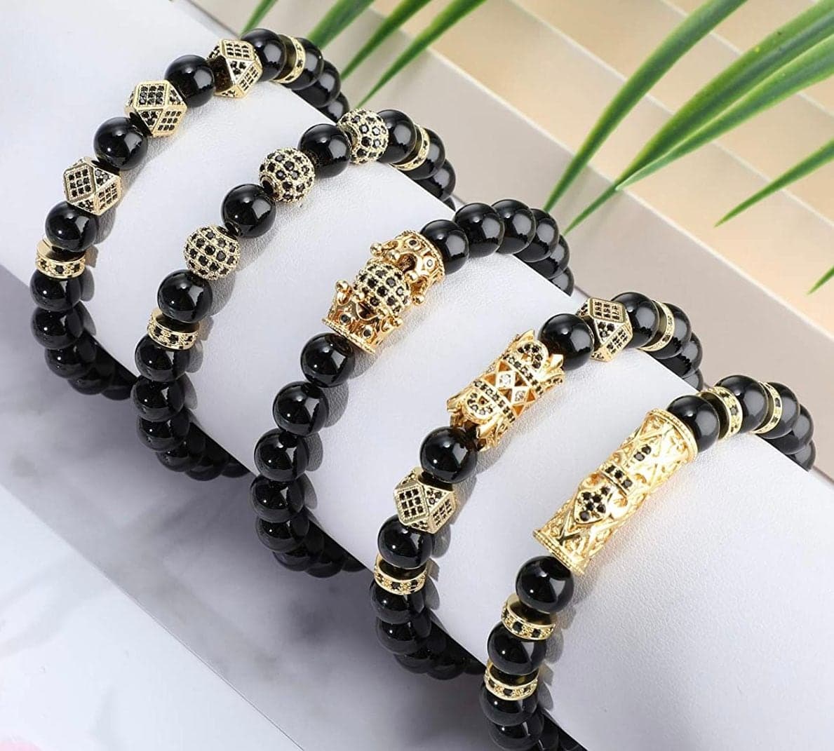 Onyx and gold beaded bracelets stacked on white